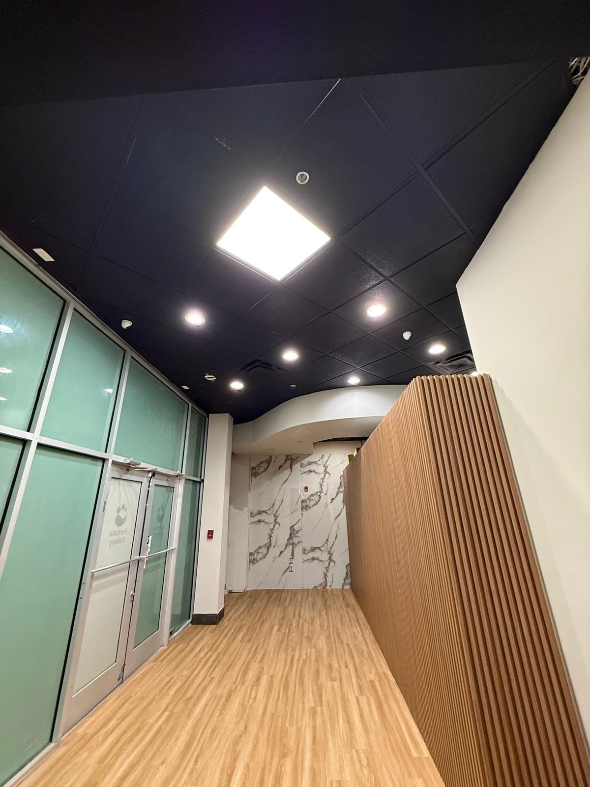 Modern commercial space with black grid ceiling, mint glass partition and marble wall feature. Third Coat Orlando