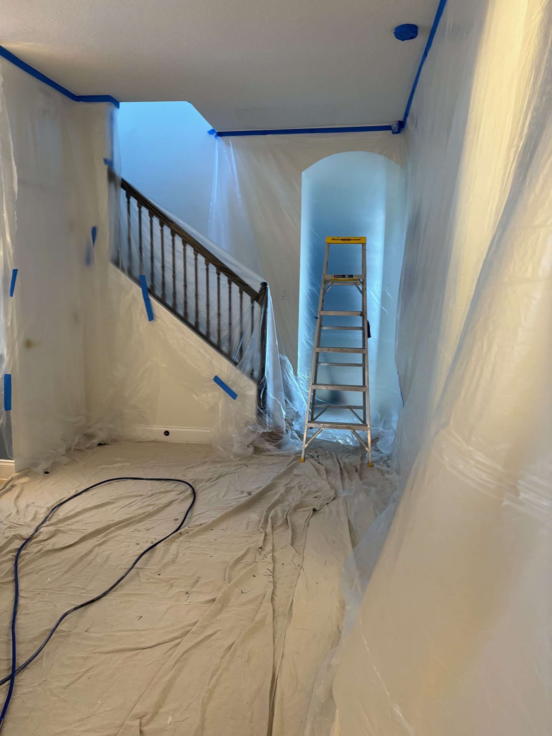 Full room protection setup before drywall repair, plastic sheeting, drop cloths, blue tape