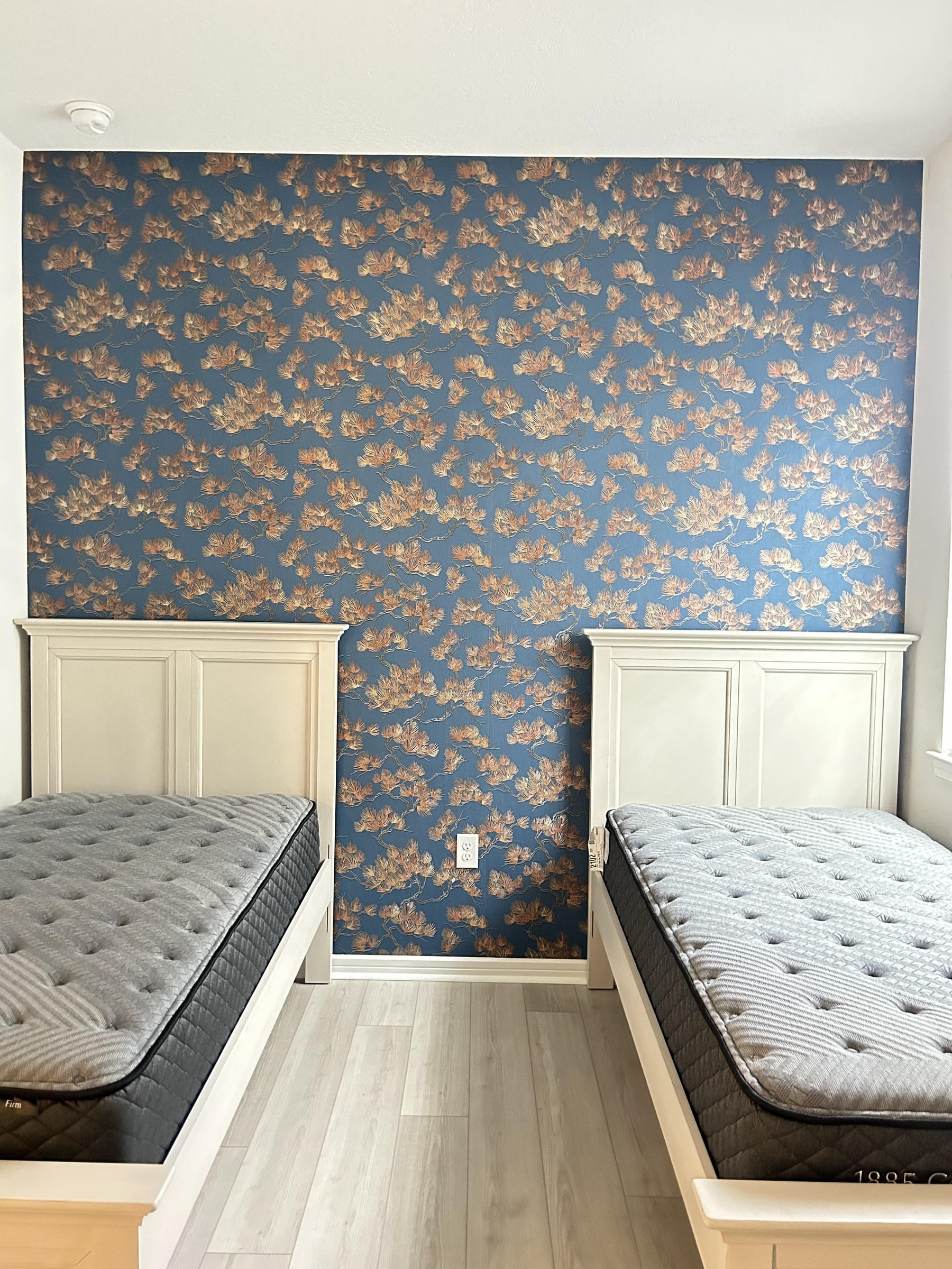 Bedroom accent wall with navy blue and copper magnolia floral wallpaper between two twin beds, Third Coat Winter Garden