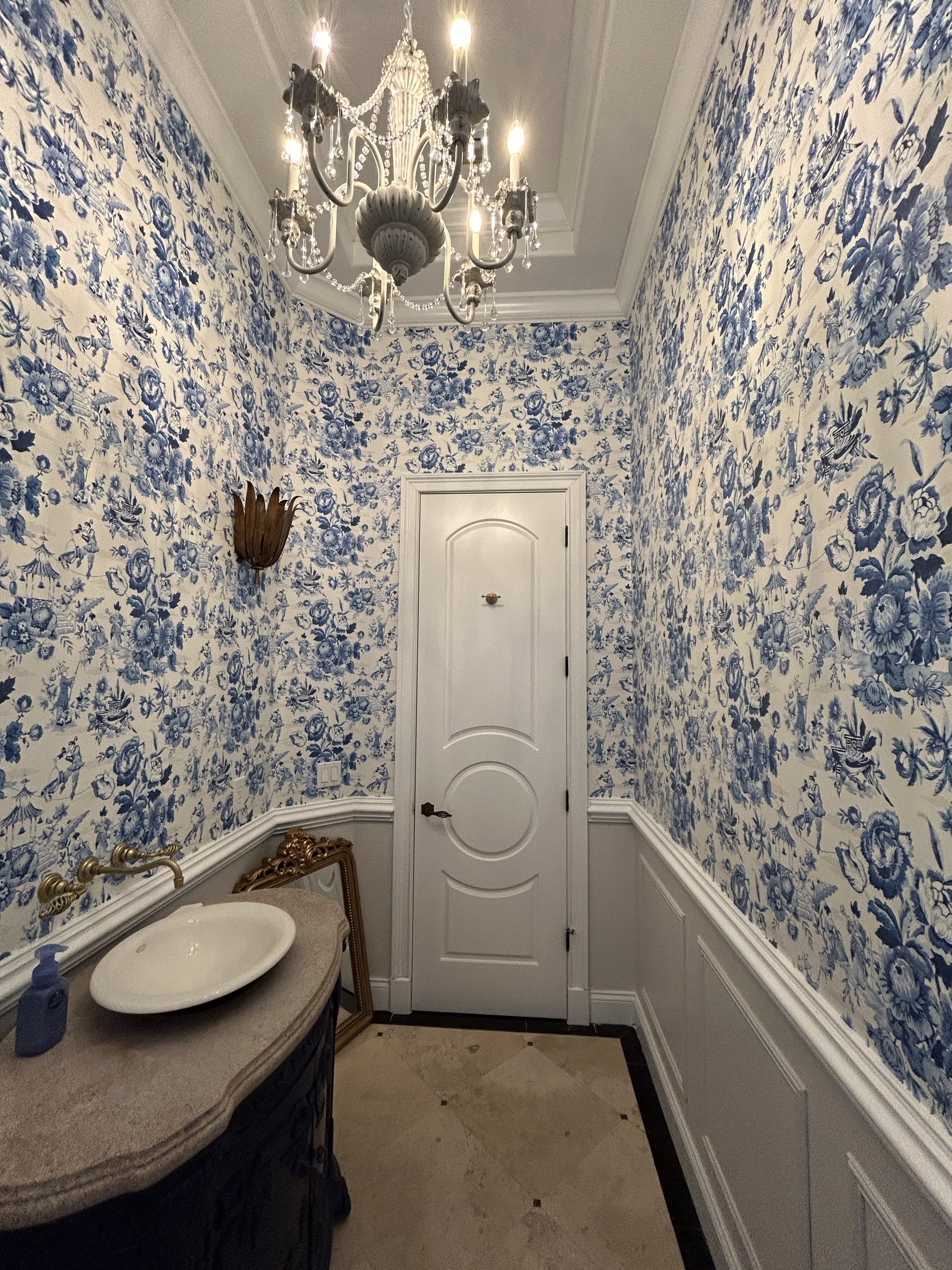 Luxury powder room with blue and white toile floral wallpaper floor to ceiling, crystal chandelier, Third Coat Orlando
